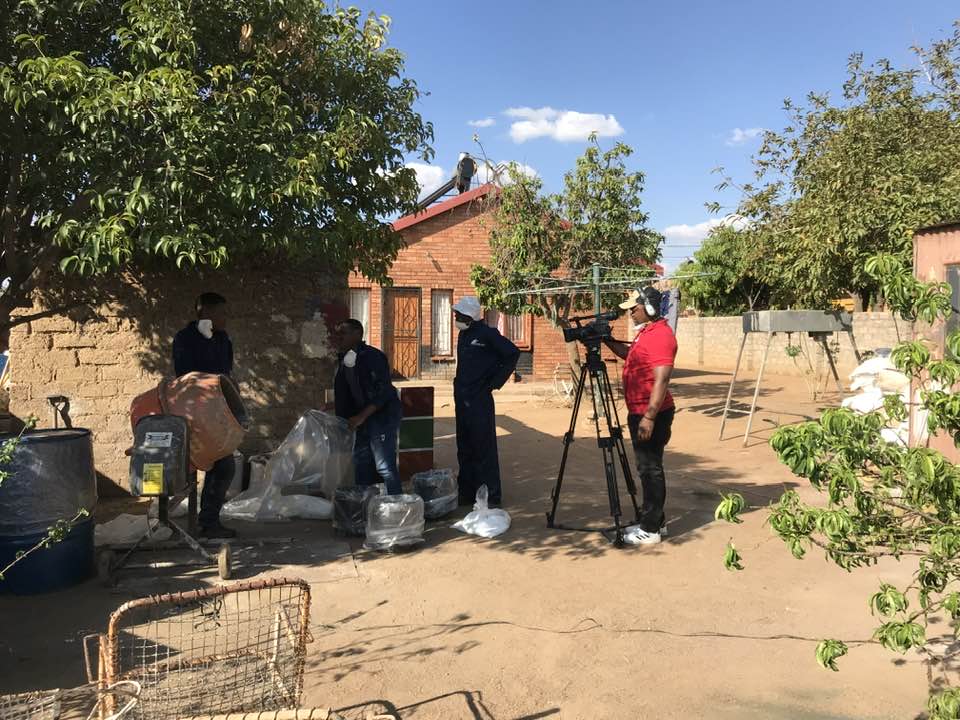 People gathered beside a brick building and camera equipment
